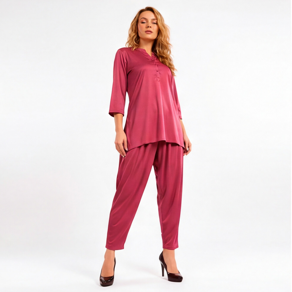 Woman wearing a rosewood pink two-piece lounge set with a tunic-style top, three-quarter sleeves, and matching tapered pants.