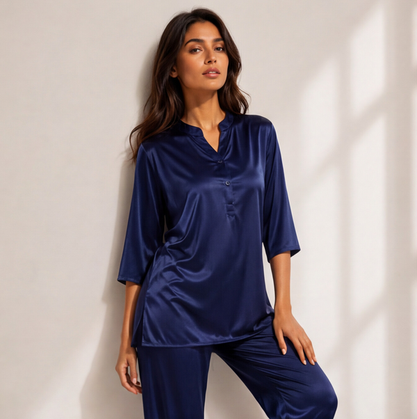 Woman wearing a midnight sapphire blue satin-look lounge set with a split-neck top, three-quarter sleeves, and matching straight-leg pants.