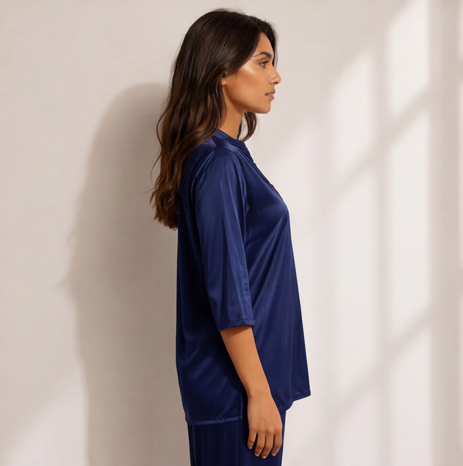Woman wearing a midnight sapphire blue satin-look lounge set with a split-neck top, three-quarter sleeves, and matching straight-leg pants.