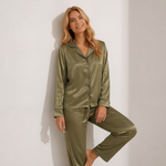 Woman wearing a green satin pajama set against a white background