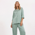 Woman wearing a light green pajama set on a white background