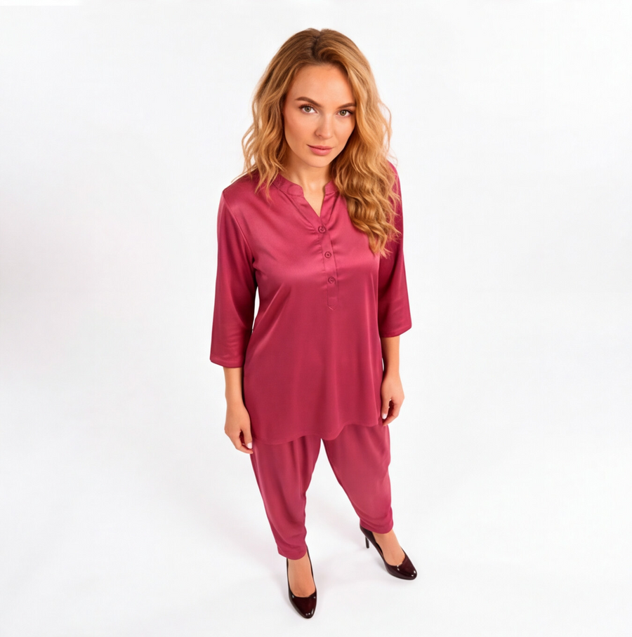 Woman wearing a rosewood pink two-piece lounge set with a tunic-style top, three-quarter sleeves, and matching tapered pants.