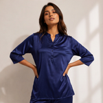 Woman wearing a midnight sapphire blue satin-look lounge set with a split-neck top, three-quarter sleeves, and matching straight-leg pants.