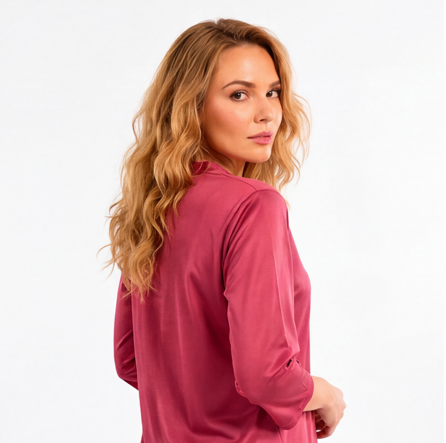 Woman wearing a rosewood pink two-piece lounge set with a tunic-style top, three-quarter sleeves, and matching tapered pants.