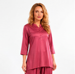 Woman wearing a rosewood pink two-piece lounge set with a tunic-style top, three-quarter sleeves, and matching tapered pants.