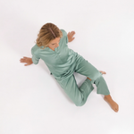Person wearing a green outfit lying on a white background