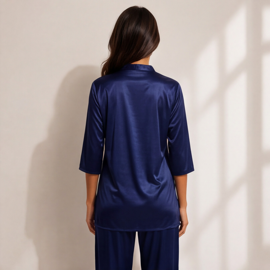 Woman wearing a midnight sapphire blue satin-look lounge set with a split-neck top, three-quarter sleeves, and matching straight-leg pants.