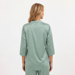 Woman wearing a light green pajama set on a white background