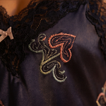 Embroidered design on a dark fabric with a bow in the background