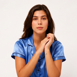 Woman wearing a blue satin pajama top against a white background